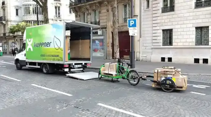 Vélo-cargo chargé de cartons à coté d'un camion 